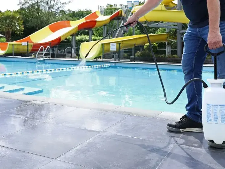 Aplicator care pulverizează tratament antialunecare pe plaja unei piscine